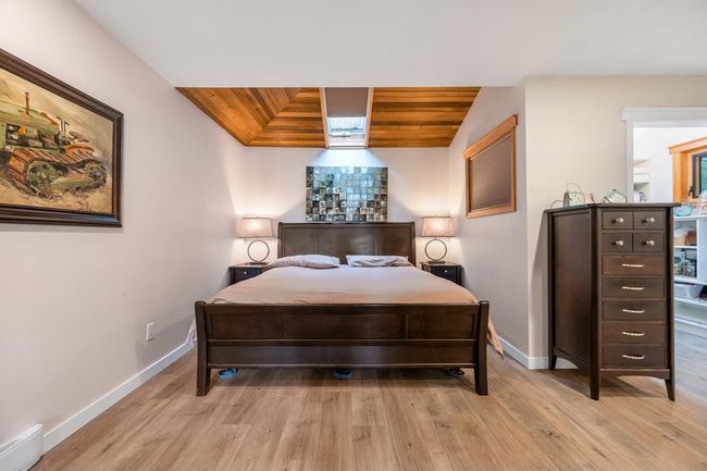 Bedroom with light wood-style flooring, wood ceiling, baseboards, and a baseboard radiator | Image 14