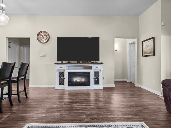 Living area featuring dark wood-style flooring and a glass covered fireplace | Image 9