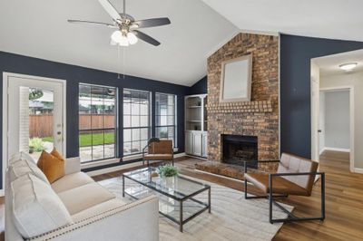 Living room featuring ceiling fan, hardwood / wood-style flooring, a brick fireplace, and vaulted ceiling | Image 1