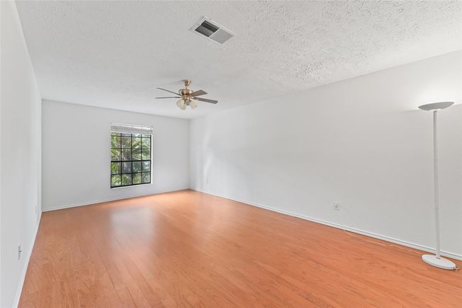 Spacious primary bedroom featuring elegant flooring, abundant natural light, and a modern ceiling fan. | Image 14