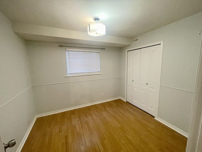Unfurnished bedroom with wood finished floors, baseboards, and a closet | Image 36