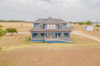 This is a two-story home with a blue exterior, featuring two converted back porches/sunrooms with remote controlled shades, and a large yard, in an open countryside setting with ample space for entertaining. Also includes a Gree mini split HVAC system for optimal energy efficiency. | Image 2