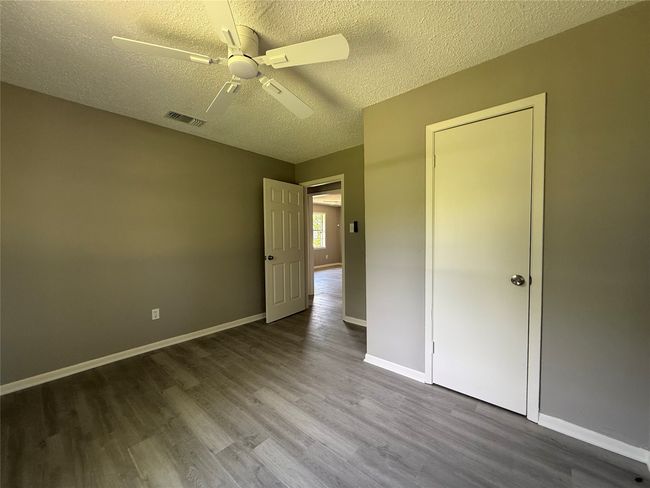 Unfurnished bedroom featuring a textured ceiling, wood finished floors, baseboards, and a ceiling fan. View 2 | Image 11