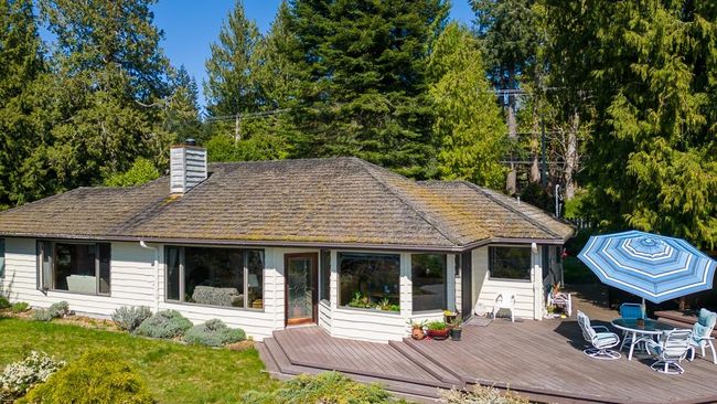 Rear view of house with a wooden deck, outdoor dining area, and a chimney | Image 6