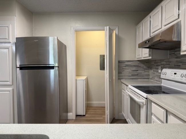 Kitchen featuring freestanding refrigerator, white electric stove, under cabinet range hood, and light countertops | Image 19