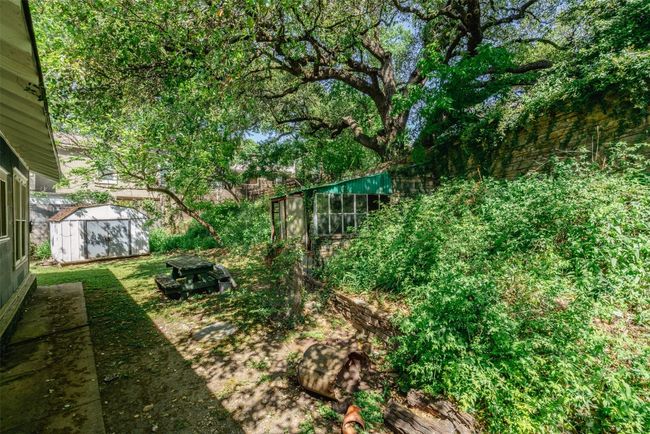 View of yard featuring an outbuilding and an old greenhouse. | Image 4