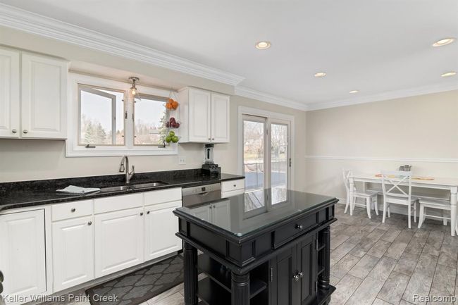 The kitchen is clean & spacious with white cabinets, granite counters & a doorwall to the patio. | Image 4