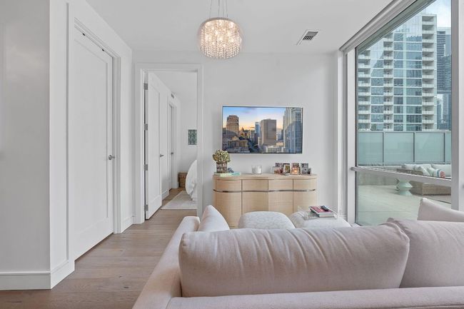 Living room with wood finished floors, a chandelier, a skyline view, a wall of windows, and baseboards | Image 12