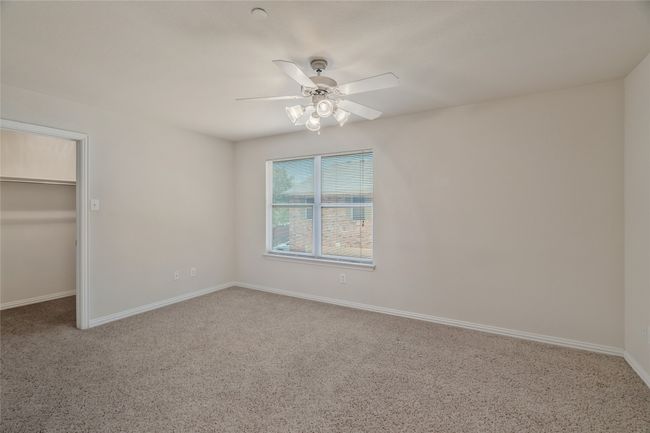 Unfurnished bedroom featuring a spacious closet, baseboards, a ceiling fan, and carpet | Image 21
