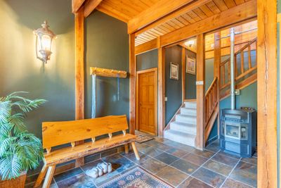 Entry with warming pellet stove, coat closet, hooks, and log bench. Prep here for your outdoor adventures. | Image 3