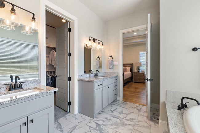 Full bath featuring marble finish floor, two vanities, a sink, and a wealth of natural light | Image 19