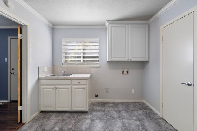 Clothes washing area with cabinet space, washer hookup, crown molding, a textured ceiling, and baseboards | Image 21