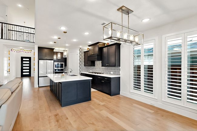 Kitchen featuring stainless steel appliances, light countertops, tasteful backsplash, light wood-style flooring, and hanging light fixtures | Image 9