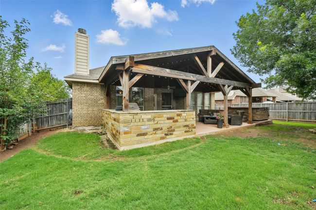 Rear view of property featuring a fenced backyard, a chimney, brick siding, and a patio area | Image 4