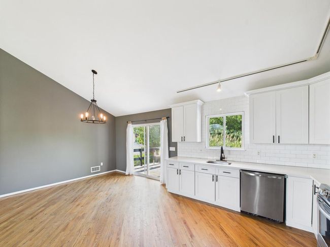 Kitchen featuring appliances with stainless steel finishes, light countertops, decorative backsplash, white cabinets, and lofted ceiling | Image 9