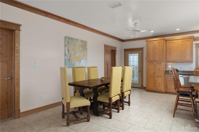 Tiled dining room with ceiling fan and crown molding | Image 5