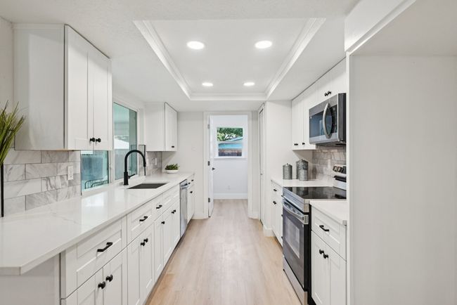 Kitchen featuring appliances with stainless steel finishes, recessed lighting, backsplash, light wood finished floors, and white cabinetry | Image 21