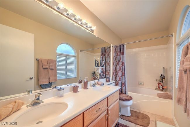 Bathroom with shower / bathtub combination with curtain, double vanity, and tile patterned flooring | Image 17