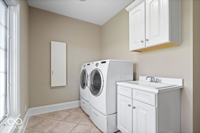 Large upstairs laundry room with utility sink, extra cabinets and a closet for storage. | Image 46