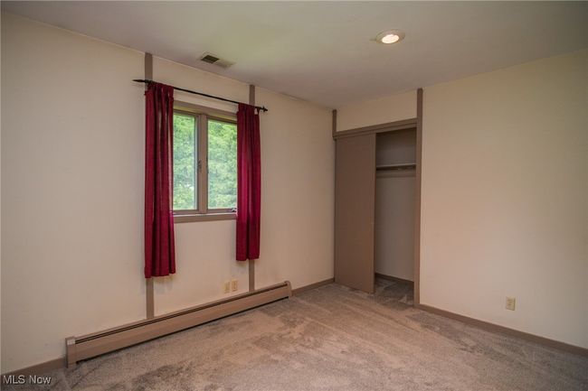 Unfurnished bedroom featuring a baseboard radiator, light colored carpet, a closet, and baseboards | Image 15