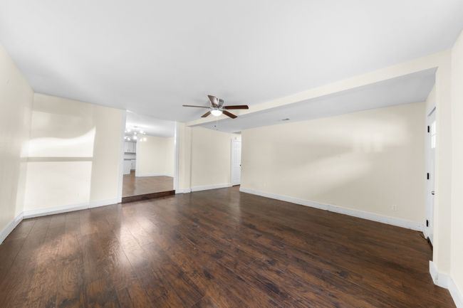 Unfurnished living room with a ceiling fan, wood-type flooring, baseboards, and a chandelier | Image 5