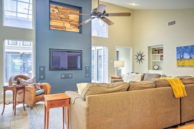 Living Room mounted television (wired to closet) with built in shelves, visible vents, high vaulted ceiling, and a ceiling fan | Image 16