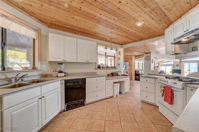 Kitchen featuring black dishwasher, gas range gas stove, a sink, wood ceiling, and white cabinets | Image 32