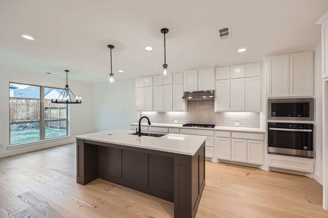 Kitchen with a sink, a chandelier, stainless steel appliances, under cabinet range hood, and decorative backsplash | Image 9