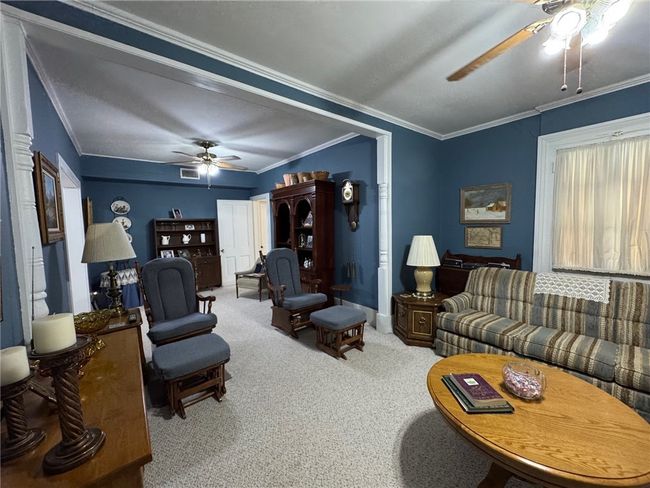 Living room with ceiling fan, carpet flooring, and ornamental molding | Image 8