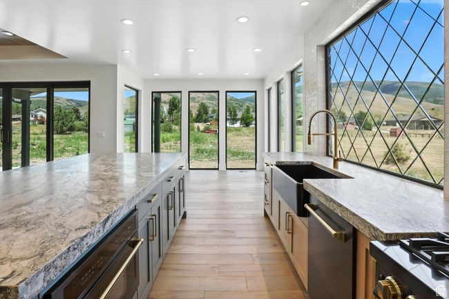 Kitchen with dishwasher, recessed lighting, light wood-style floors, light stone counters, and range | Image 9