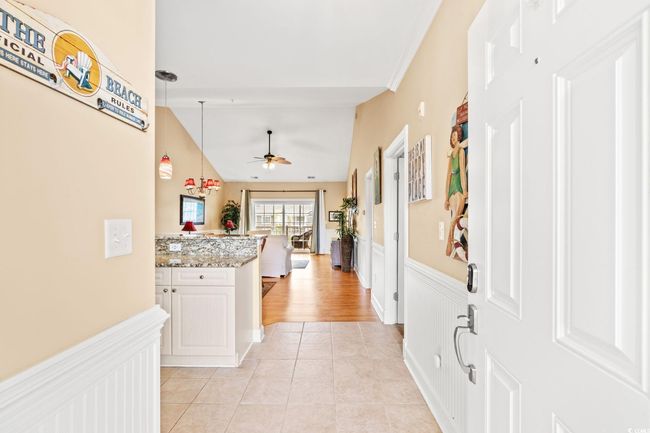 Hall featuring a wainscoted wall, lofted ceiling, and light tile patterned flooring | Image 21