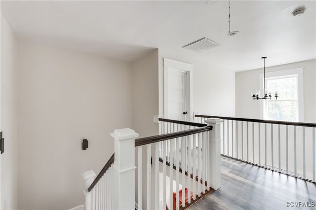 Hallway with visible vents, wood finished floors, an upstairs landing, and a notable chandelier | Image 29
