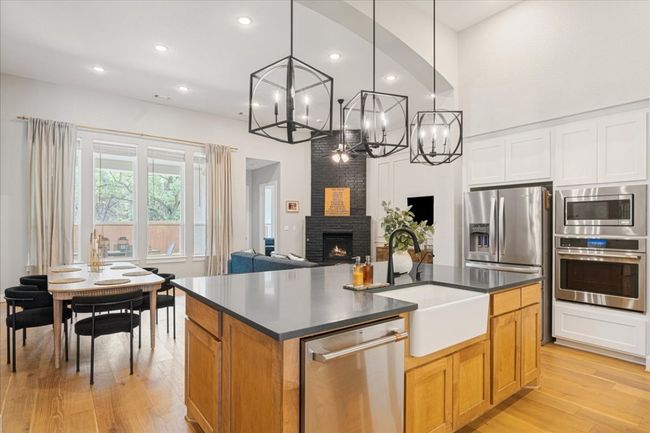 Kitchen with stainless steel appliances, a sink, a chandelier, dark countertops, and recessed lighting | Image 13