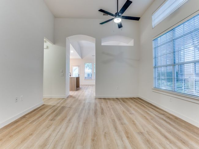 Empty room featuring high vaulted ceiling, arched walkways, ceiling fan, and wood finished floors | Image 6