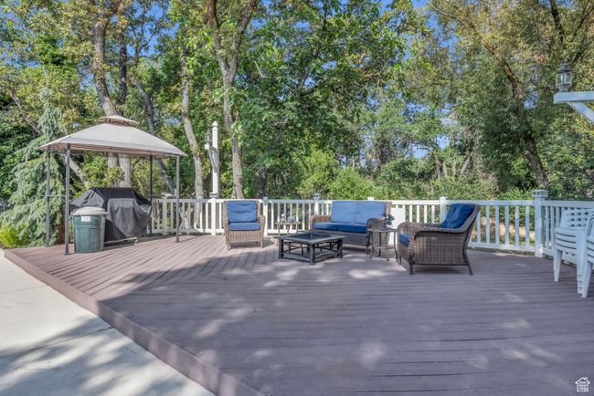 Pool area. Wooden deck with an outdoor hangout area, area for grilling, a gazebo, and view of scattered trees | Image 38