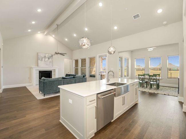 The kitchen is a culinary masterpiece, featuring an expansive island perfect for entertaining, quartz countertops, sleek white cabinetry with glass display fronts, an apron-front farm sink, and high-end stainless-steel appliances, including a six-burner gas cooktop and double convection oven. | Image 9