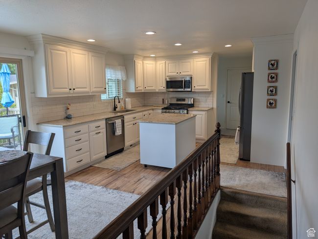 Kitchen with appliances with stainless steel finishes, a sink, light wood-type flooring, white cabinetry, and recessed lighting | Image 11