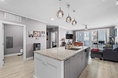 Kitchen featuring sink, light hardwood / wood-style floors, light stone countertops, ceiling fan, and ornamental molding | Image 3