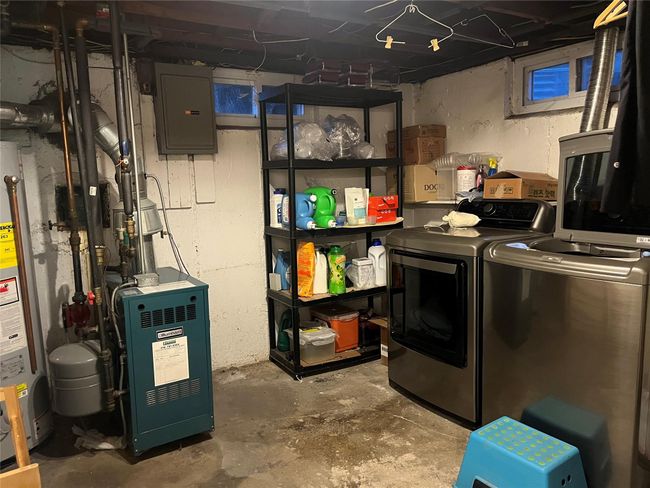 Unfinished below grade area with water heater, independent washer and dryer, a heating unit, and electric panel | Image 16
