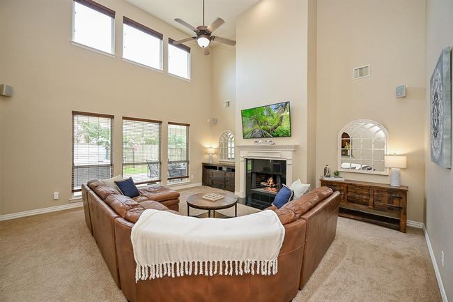 A warm and inviting living room with an impressive two-story ceiling that adds grandeur and openness to the space. | Image 7