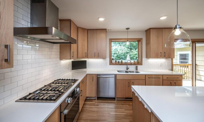 Gas stove, tile backsplash, kitchen window & hardwood floors. | Image 4