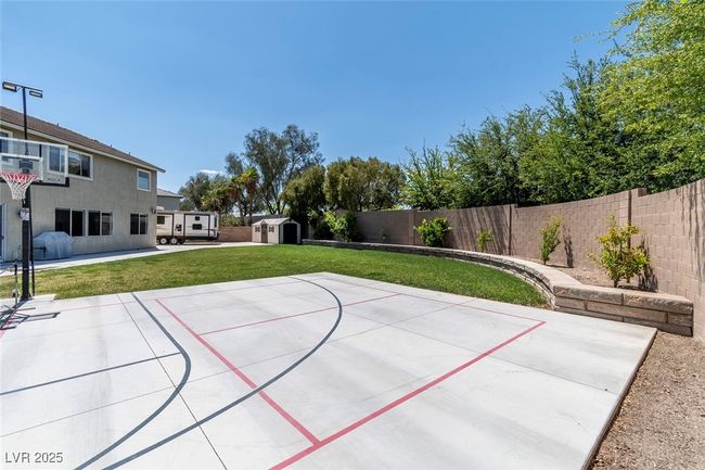 View of sport court with a fenced backyard, basketball hoop, a storage unit, and a yard | Image 40