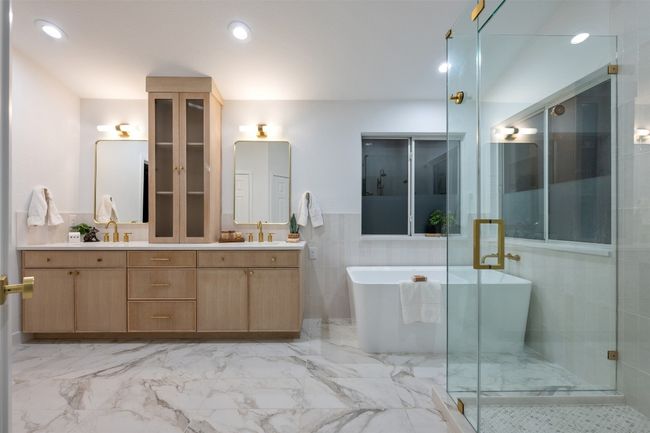 Bathroom featuring double vanity, a stall shower, a soaking tub, marble finish floor, and a sink | Image 24