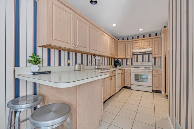 Kitchen featuring light brown cabinetry, white appliances, light countertops, and recessed lighting | Image 9