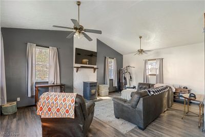 Living room featuring dark wood-type flooring, lofted ceiling, ceiling fan, and a wood stove | Image 3