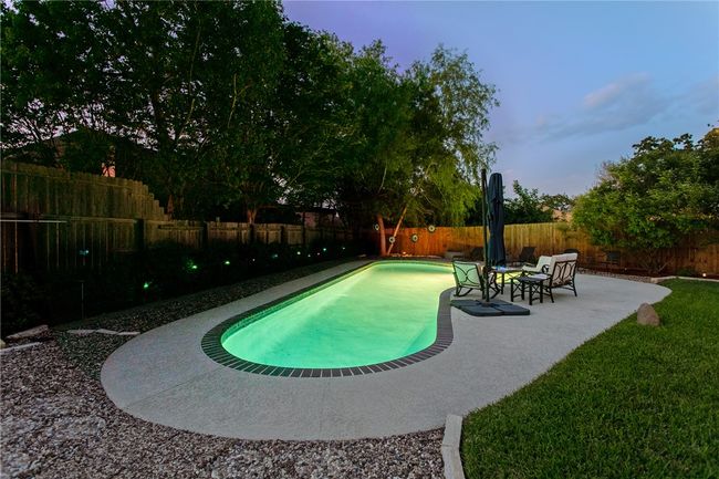 View of swimming pool with a patio area and a fenced backyard | Image 42