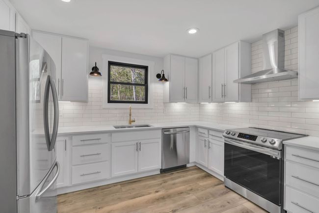 Gorgeous new kitchen with white shaker style cabinets, quartz countertops, tiled backsplash, under counter lighting, and SS appliances. | Image 13