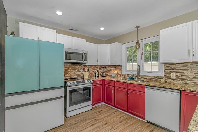 Kitchen featuring appliances with stainless steel finishes, decorative backsplash, white cabinetry, and recessed lighting | Image 11