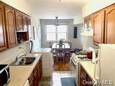 Kitchen featuring appliances with stainless steel finishes, extractor fan, light tile patterned flooring, sink, and decorative light fixtures | Image 2