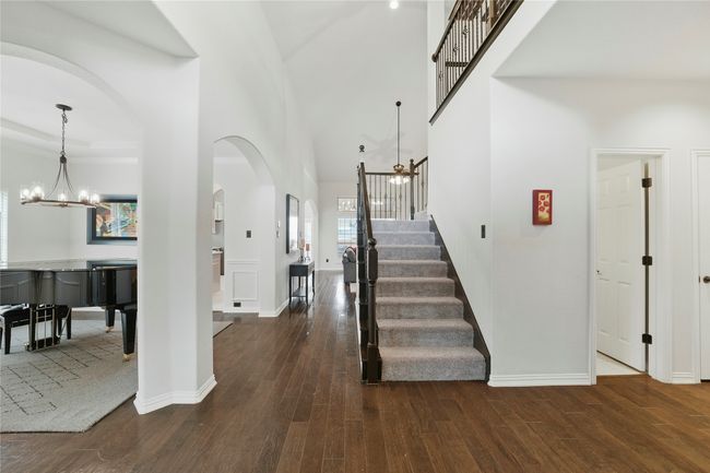 Foyer with a chandelier, arched walkways, wood finished floors, and stairway | Image 4
